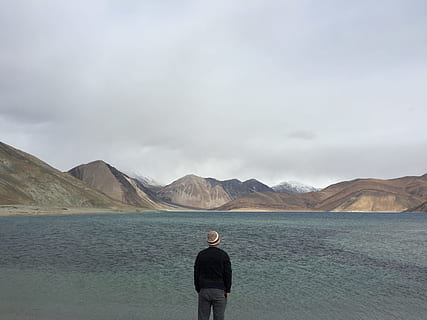 sky, man, water, clouds, back view, cloudy, gloomy, idyllic, lake, looking, mountain range, scenery, scenic, tranquil, traveller, wanderlust, one person, rear view, mountain, standing, cloud - sky, scenics - nature, adult, men, nature, environment, land, remote, day, beauty in nature, solitude, landscape, copy space, outdoors, contemplation, looking at view, 2K, CC0, public domain, royalty free