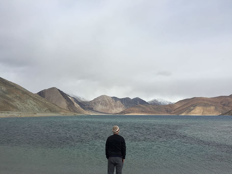 sky, man, water, clouds, back view, cloudy, gloomy, idyllic, lake, looking, mountain range, scenery, scenic, tranquil, traveller, wanderlust, one person, rear view, mountain, standing, cloud - sky, scenics - nature, adult, men, nature, environment, land, remote, day, beauty in nature, solitude, landscape, copy space, outdoors, contemplation, looking at view, 2K