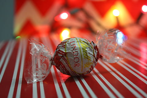 chocolate, present, gift, candy, lindt, lindor, candy cane, white chocolate, sweet, xmas, dessert, sugar, close-up, red, celebration, indoors, no people, holiday, decoration, christmas, focus on foreground, illuminated, food and drink, christmas decoration, selective focus, striped, shape, pattern, group of objects, sphere, christmas ornament, glass, 4K, CC0, public domain, royalty free