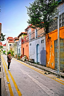 uomo, Marrone, bianca, camicia, in piedi, davanti, blu, arancia, rosa, beige, calcestruzzo, costruzione, verde, albero delle foglie, blu, arancione, foglia verde, albero, strada, architettura, scena urbana, vecchio, esterno dell'edificio, città, struttura costruita, Casa, culture, cittadina, all'aperto, persone, vicolo, vita di città, viaggio, solo un uomo, una persona, lunghezza intera, adulto, persone reali, stili di vita, cielo, giorno, natura, uomini, mezzi di trasporto, a piedi, retrovisore, attività di svago, 4K, CC0, dominio pubblico, privo di copyright