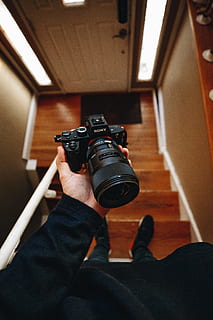persona, participación, negro, cámara sony dslr, escalera, manga larga, camisa, en pie, marrón, de madera, ningún hombre, todo lo que, ese poder, sony, cámara, mano, lente, camara - equipo fotografico, temas de fotografia, fotógrafo, lente - instrumento óptico, aficiones, equipo, fotografiando, cámara digital, fotografía, cámara réflex, una persona, gente real, tecnología, adentro, actividad de ocio, estilos de vida, perspectiva personal, actividad, equipo fotográfico, hombres, parte del cuerpo humano, mano humana, persona irreconocible, moderno, techo, pantalones, 4K, CC0, dominio público, libre de derechos