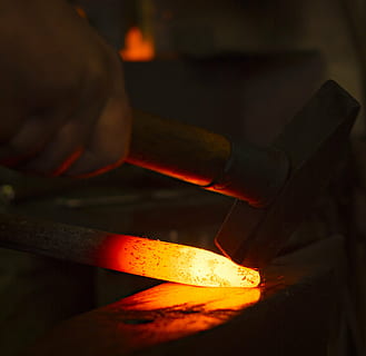 persona que sosté el martell, forjar, artesania, enclusa, foc - fenomen natural, flama, material de fusta, mà humana, indústria, calor - temperatura, indústria del metall, a l'interior, taller, cremant, eina de treball, foc, fabricació, brillant, treball, art i artesania, primer pla, foneria, fusió, metall, ocupació, habilitat, ferro - metall, aliatge, acer, espurnes, 2K, CC0, domini públic, lliure de regalies