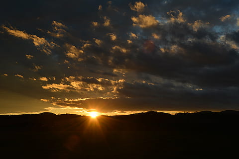 sky, clouds, sunset, spotlight, evening sky, clouds form, dark, covered sky, nikon d5200, cloud - sky, beauty in nature, scenics - nature, tranquility, tranquil scene, sunlight, landscape, silhouette, environment, sunbeam, dramatic sky, orange color, idyllic, nature, sun, non-urban scene, no people, cloudscape, outdoors, bright, lens flare, 5K, CC0, public domain, royalty free