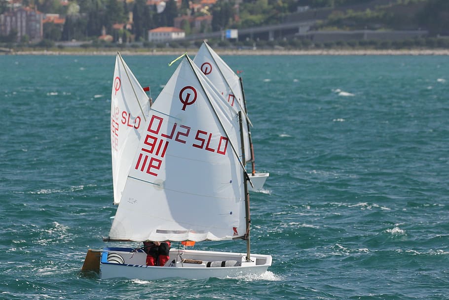 vela, optimista, ioda, sol, mar, navegar, nàutica, vaixell, vent, veler, mariner, esport, onada, competició, jove, aigua, text, comunicació, vaixell nàutic, dia, cap gent, a l'aire lliure, primer pla, naturalesa, transport, manera de transport, guió occidental, viatjar, davant del mar, nombre, moviment, Color blanc, llum solar, ferri, embarcacions de passatgers, creuer, 2K