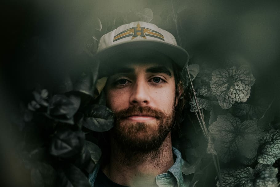 poc profund, focalitzar la fotografia, home, amagar-se, verd, plantes, de peu, al costat, flor, durant el dia, planta, barba, barret, full, persona, pèl facial, forces Armades, retrat, militar, mirant la càmera, casc, adult, una persona, casc de treball, tirada al cap, barreteria, homes, govern, adult jove, a l'interior, exèrcit, roba, uniforme, bigoti, 5K