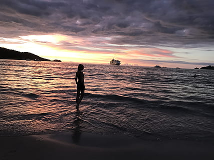 Frau, Karosserie, Wasser, hinterleuchtet, Strand, Wolken, Dämmerung, Abend, Horizont, Insel, Landschaft, Berg, Natur, Ozean, draußen, Person, Reflexionen, Sand, Meer, seelandschaft, Schiffe, Ufer, Silhouette, Himmel, Sonne, Sonnenuntergang, Wellen, wolke - himmel, Schönheit in der Natur, echte Menschen, Szenen - Natur, Land, Lebensstile, eine Person, Freizeitbeschäftigung, Stehen, orange Farbe, Ruhe, idyllisch, Horizont über Wasser, 4K