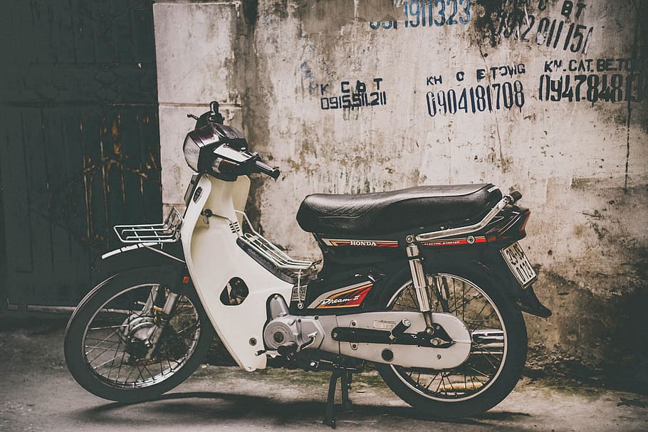 blanc, negre, motocicleta de subjecció, aparcat, paret, al costat, edifici, durant el dia, eix vertebrador, moto, motoneta, transport, mode de transport, vell, vehicle terrestre, estacionari, dia, cap gent, manera de transport, funció de construcció de parets, estructura construïda, arquitectura, exterior de l'edifici, aparcament, text, ciutat, carrer, tricicle, guió occidental, a l'aire lliure, bicicleta, comunicació, roda, 5K