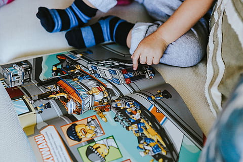 child reading, comic, story, Child, reading, kid, baby, lego, people, close-up, one person, human body part, indoors, human hand, technology, hand, real people, high angle view, holding, midsection, repairing, boys, connection, offspring, childhood, selective focus, adult, complexity, 5K