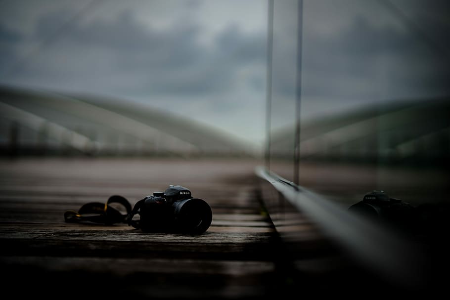 fotocamera dslr nera, telecamera, nikon, bokeh, riflessione, Tech, messa a fuoco selettiva, nessuno, nuvola - cielo, cielo, mezzi di trasporto, giorno, natura, livello di superficie, avvicinamento, all'aperto, veicolo terrestre, modo di trasporto, auto, strada, città, tecnologia, velocità, veicolo a motore, legno - materiale, 5K