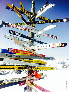 brunt træpost, stolpe, retning, ski, mål, vejviser, pil, skilte, bjerge, stå på ski, by, udendørs, ingen mennesker, dag, bygning udvendig, bybilledet, sne, vinter, natur, tekst, kold temperatur, himmel, arkitektur, meddelelse, hængende, bygget struktur, multi farvet, bjerg, skyfri himmel, rejse, flag, snedækket bjerg, 1080P, CC0, offentligt domæne, royaltyfrie