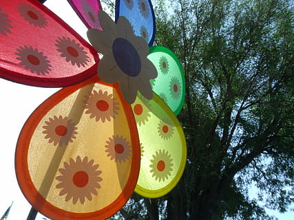 molí de vent, primavera, arbre, naturalesa, verd, vent, flors, molí, decoració, vermell, taronja, groc, blau, colorit, patró, vista d’angle baix, cap gent, planta, multicolor, dia, cel, creativitat, forma, art i artesania, cercle, primer pla, forma geomètrica, disseny, a l'aire lliure, penjant, metall, motiu floral, directament a sota, roda, 4K, CC0, domini públic, lliure de regalies