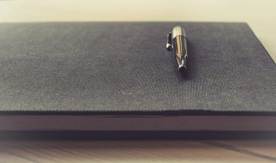 black twist pen, notepad, pen, business, notebook, office, paper, write, writing, paperwork, pad, close-up, indoors, metal, selective focus, still life, no people, simplicity, two objects, wood - material, jewelry, table, high angle view, ring, shiny, connection, furniture, equipment, technology, copy space, working, personal accessory, silver colored, 2K, CC0, public domain, royalty free