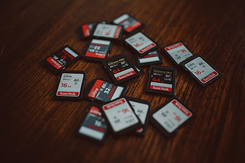 camera, Memory cards, technology, gambling, indoors, no people, wood - material, table, large group of objects, communication, text, still life, selective focus, high angle view, close-up, western script, wood, red, variation, luck, choice, positive emotion, day, focus on foreground, 4K, CC0, public domain, royalty free