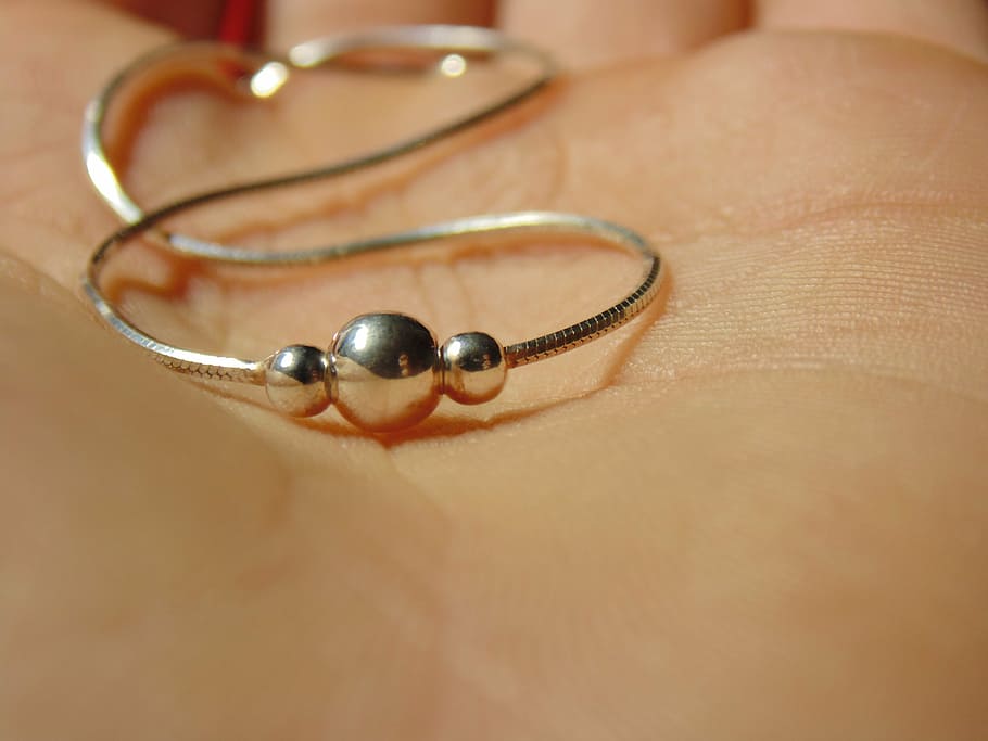 polsera, plata, mà, joieria, primer pla, una persona, part del cos humà, a l'interior, anell, enfocament selectiu, part del cos, moda, accessori personal, mà humana, tir de l'estudi, pell humana, riquesa, pell, metall, luxe, joies de perles, 5K