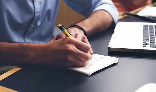 person, writing, notes, macbook, pro, man, white, paper, black, brown, wooden, table, working, notepad, pen, business, desk, office, human hand, only men, computer, holding, wireless technology, men, adult, occupation, hand, one person, human body part, sitting, book, close-up, note pad, publication, indoors, education, 4K, CC0, public domain, royalty free