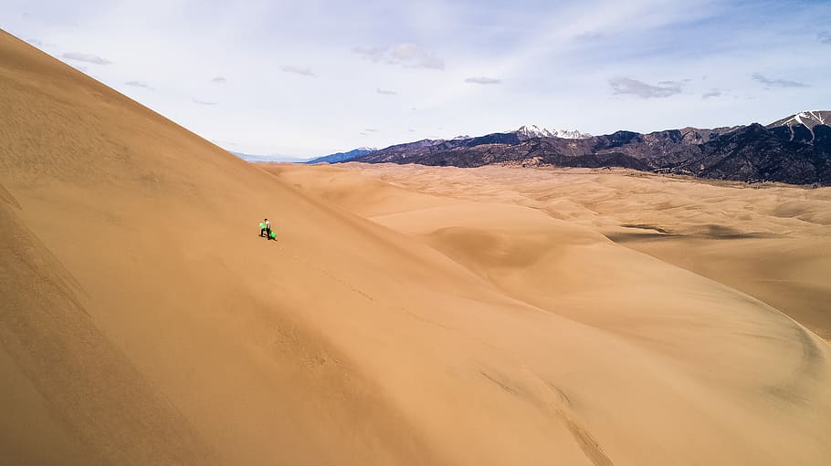 persona, se senti, desert, clar, blau, cel, durant el dia, de peu, camp del desert, duna, sorra, Serra, muntanya, gent, caminar, pissarra, amunt, bronzejat, bonic, drone, senderisme, caminada, a l'aire lliure, persones a la natura, neu, sandboard, snowboard, terra, duna de sorra, paisatge, medi ambient, escenics - natura, bellesa a la natura, clima àrid, naturalesa, transport, viatjar, manera de transport, clima, núvol - cel, sec, destinacions de viatge, vehicle utilitari esportiu, 5K