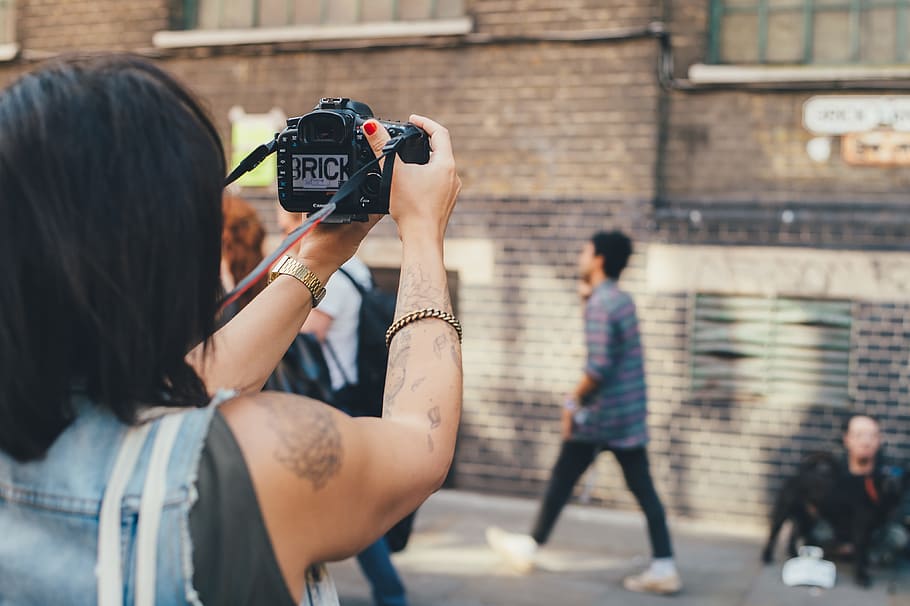 persona, presa, foto, calcestruzzo, costruzione, detenzione, telecamera, davanti, donna in blu, denim, senza maniche, superiore, nero, fotocamera dslr, Fotografare, macchina fotografica - attrezzatura fotografica, fotografo, persone, turista, le riprese, all'aperto, temi fotografici, donne, scena urbana, uomini, Camera digitale, città, persone reali, attività, tecnologia, architettura, stili di vita, esterno dell'edificio, attrezzatura fotografica, gruppo di persone, adulto, struttura costruita, giorno, tecnologia wireless, fotocamera reflex digitale con obiettivo singolo, 4K