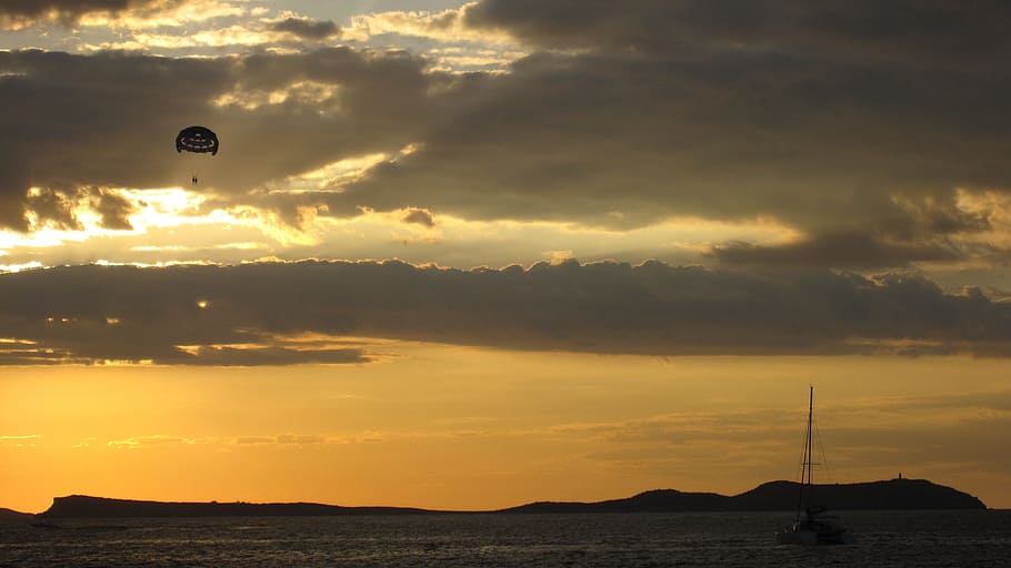 solnedgang, sol, vest, lys, hav, solen, aften, natur, tusmørke, kysten, himmel, parakite, båd, vandsport, sejlbåde, helligdage, sommer, hvile, udsigt, landskab, Ibiza, sky - himmel, ingen mennesker, udendørs, skønhed i naturen, vand, scenics - natur, transportmidler, silhuet, orange farve, rolig scene, ro, bjerg, flyvende, Midt i luften, jord, sejlbåd, 2K