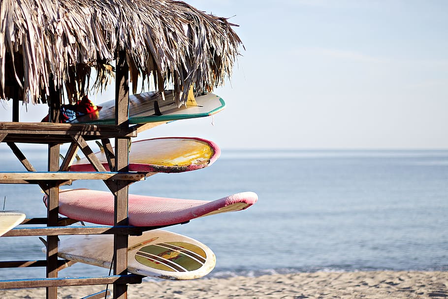 vermell, blanc, taula de surf, marró, fusta, prestatge, taules de surf, refugi, navega, botiga, estiu, platja, mar, vacances, línia de costa, sorra, a l'aire lliure, aigua, relaxació, clima tropical, naturalesa, idíl·lic, destinacions de viatge, cap gent, llocs de viatges, complex turístic, blau, cel, escena tranquil·la, viatjar, platges, paraigua, dia, terra, horitzó sobre l’aigua, bellesa a la natura, festa, horitzó, tranquil·litat, escenics - natura, centrar-se en primer pla, viatge, 5K
