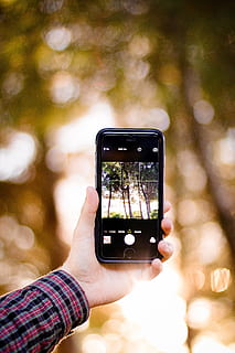 boke photography, person, holding, iphone 6, displaying, trees, hand, camera, iphone, smartphone, taking photo, photographer, photography, technology, mobile phone, bokeh, digital, touchscreen, touch, pov, smart phone, portable information device, wireless technology, photography themes, photographing, human hand, communication, real people, one person, tree, human body part, focus on foreground, screen, leisure activity, nature, telephone, outdoors, finger, 5K, CC0, public domain, royalty free