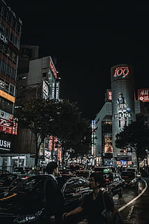 two, person, standing, cars, street, architecture, building, infrastructure, blue, sky, skyscraper, tower, city, skyline, car, vehicle, traffic, people, walking, men, road, dark, night, lights, city life, city street, building exterior, illuminated, large group of people, built structure, transportation, mode of transportation, real people, motor vehicle, land vehicle, group of people, nature, outdoors, office building exterior, cityscape, 5K