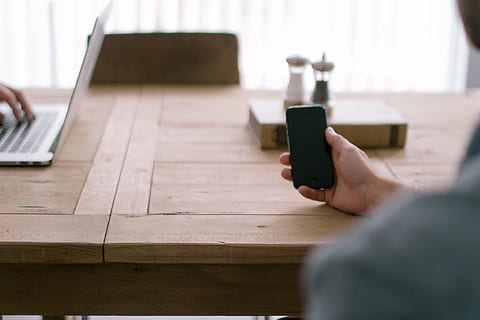 person, holding, smartphone, desk, black, leaning, brown, wooden, table, iphone, hand, man, work, macbook, laptop, technology, business, wood, chair, book, salt, pepper, meeting, wireless technology, one person, human hand, indoors, selective focus, one man only, connection, communication, human body part, adult, computer, convenience, smart phone, portable information device, working, mobile phone, using laptop, 5K, CC0, public domain, royalty free