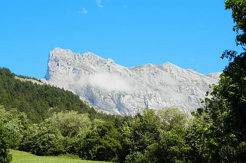 muntanya, cel blau, arbre, núvol, blau, cel, gris, roche, rocós, avet, paisatge, paisatge de muntanya, verd, vegetació, prada, naturalesa, a l'aire lliure, escenics, cim de muntanya, estiu, planta, bellesa a la natura, escenics - natura, tranquil·litat, creixement, cel clar, color verd, dia, escena tranquil·la, cap gent, vista d’angle baix, escena no urbana, llum solar, medi ambient, bosc, muntanya nevada, 4K, CC0, domini públic, lliure de regalies