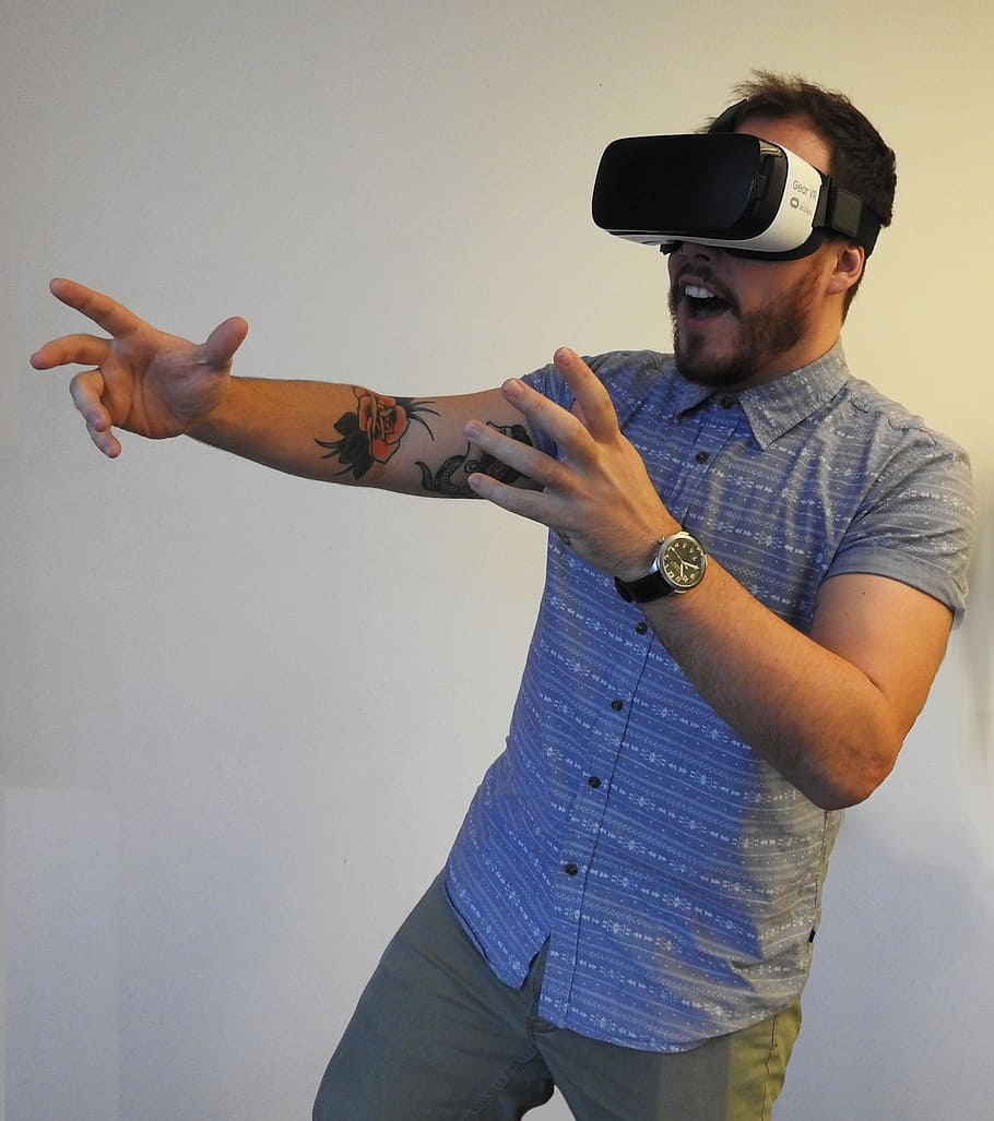 home, portar, blanc, negre, gear vr, realitat virtual, oculus, tecnologia, la realitat, virtual, auriculars, entreteniment, futurista, dispositiu, una persona, persones reals, home jove, tres quarts de longitud, estils de vida, homes, adult jove, moda, de peu, gesticulant, gots, activitat d'oci, mà, a l'interior, mà humana, funció de construcció de parets, vista frontal, roba casual, mig adult, rellotge de polsera, braç humà, 2K