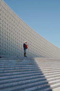 man, standing, stairs, alone, top, staircase, holding, phone, ears, airplane, flying, sky background, minimalistic, white, pattern, blue sky, steps, architecture, sky, one person, day, clear sky, nature, blue, men, full length, sunlight, built structure, rear view, outdoors, building exterior, real people, adult, sunny, walking, 1080P, CC0, public domain, royalty free