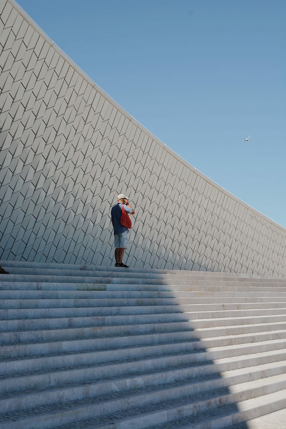 uomo, in piedi, le scale, solo, superiore, scala, detenzione, Telefono, orecchie, aereo, volante, sfondo del cielo, minimalista, bianca, modello, cielo blu, passaggi, architettura, cielo, una persona, giorno, cielo sereno, natura, blu, uomini, lunghezza intera, luce del sole, struttura costruita, retrovisore, all'aperto, esterno dell'edificio, persone reali, adulto, soleggiato, a piedi, 1080P