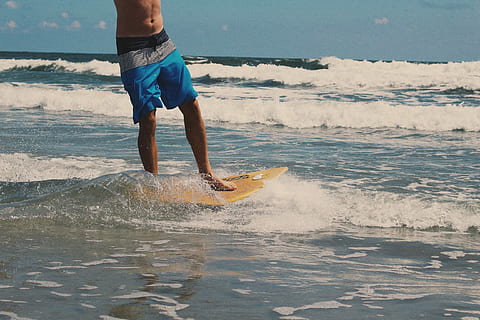 home, blau, pantalons curts de tauler, muntar a cavall, groc, skimboard, platja, tauler blau, En la platja, taula de surf, mar, surf, homes, a l'aire lliure, onada, esport, aigua, estiu, esport d'aigua, gent, navega, una persona, vacances, mascles, persones reals, activitat d'oci, naturalesa, moviment, estils de vida, terra, esport aquàtic, esquitxades, activitats de cap de setmana, bellesa a la natura, curts, 2K, CC0, domini públic, lliure de regalies