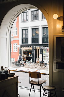 hygge, braun, schwarz, armloser Stuhl, runder Hocker, neben, Glasrahmen, Weiß, Gebäude, Straße, tagsüber, Bogen, Fenster, die Architektur, Licht, Tabelle, Sitz, Gebäudehülle, Stuhl, Cafe, Geschäft, gebaute Struktur, keine Leute, Möbel, Tür, Fokus auf den Vordergrund, Restaurant, Abwesenheit, Glas - Material, leeren, Stadt, draußen, Rahmen, 5K, CC0, gemeinfrei, lizenzfrei