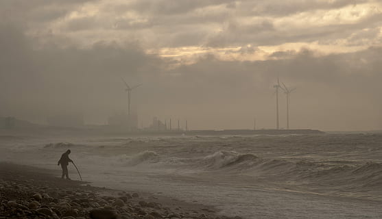 persona, caminar, vora del mar, de peu, Riba, durant el dia, aspre, vent, platja, oceà, mar, poder, molí de vent, ennuvolat, núvol, Pol · lució, gris, dramàtica, aigua, home, cel, terra, núvol - cel, una persona, medi ambient, naturalesa, aerogenerador, turbina, conservació del medi ambient, bellesa a la natura, persones reals, energia renovable, escenics - natura, generació de combustible i energia, a l'aire lliure, poder a la natura, 2K, CC0, domini públic, lliure de regalies