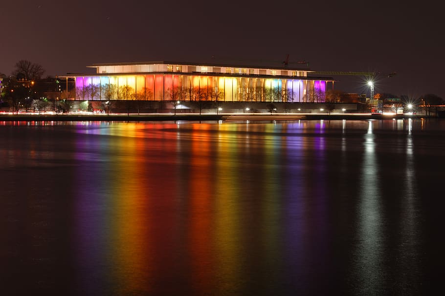 Kennedy Center, encès, edifici de vidre, nit, fosc, llums, reflexió, llac, il·luminat, aigua, arquitectura, exterior de l'edifici, estructura construïda, ciutat, cap gent, davant del mar, naturalesa, destinacions de viatge, cel, riu, transport, multicolor, porpra, edifici, equips d’il·luminació, vida nocturna, 5K
