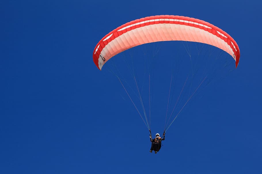 mand på faldskærm, handling, aktivitet, flyvningen, flyve, blå, flyvende, svæve, svævefly, glide, jumper, mand, faldskærm, paragliding, mennesker, rød, himmel, sport, skyfri himmel, Midt i luften, udendørs, ekstrem sport, eventyr, transportmidler, fritidsaktivitet, natur, uigenkendelig person, frihed, luftfartøj, dag, pilot, parasailing, sikkerheds sele, lodsning, 2K