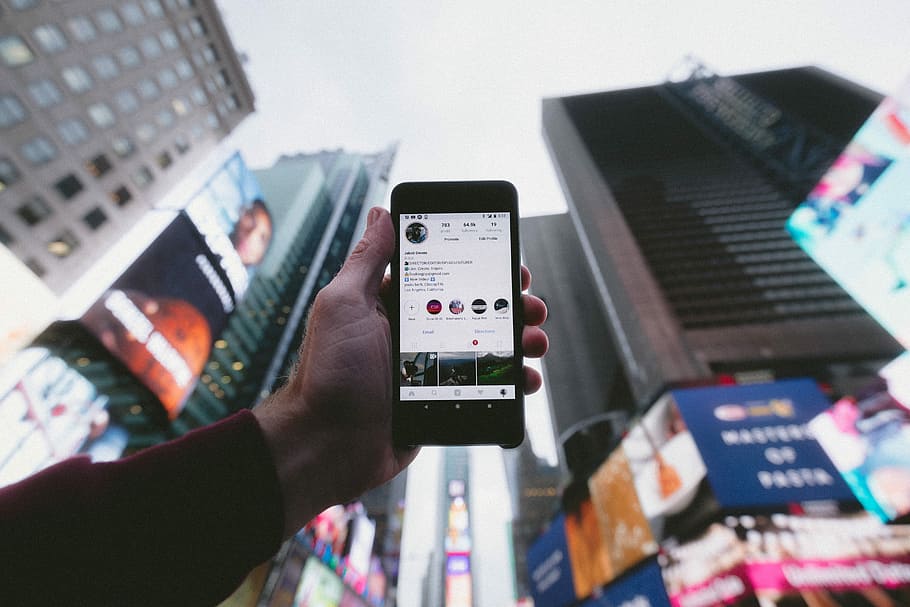 alt, foto d'angle, persona, celebració, convertit, smartphone, fons dels edificis, mostrant, enviament de Instagram, quadrat de temps, fotografia, tecnologia, fons, equipament, tecnologia sense fils, comunicació, mà humana, mà, adult, telèfon intel·ligent, connexió, dispositiu d’informació portàtil, part del cos humà, ciutat, gent, enfocament selectiu, homes, dia, telèfon mòbil, a l'aire lliure, vida de ciutat, aplicació per a mòbils, 5K