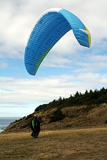 man, riding, blue, parachute, sky, diver, touching, green, grass, field, mountain, clouds, tree, paragliding, adventure, people, one person, flying, one man only, cloud - sky, mid adult, leisure activity, freedom, adults only, extreme sports, real people, land, lifestyles, nature, day, sport, environment, men, mid-air, outdoors, 4K