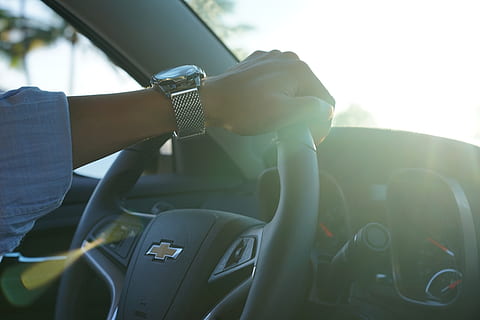 persona, conduir, cotxe Chevrolet, durant el dia, cotxe, mà, rellotge, gestionar, manera de transport, transport, automòbil, vehicle terrestre, dia, homes, estils de vida, persones reals, viatjar, volant, llum solar, adult, a l'aire lliure, activitat d'oci, gent, interior del vehicle, centrar-se en primer pla, interior del cotxe, flare de la lent, extremitat humana, 5K, CC0, domini públic, lliure de regalies
