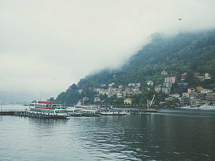 boat, houses, daytime, passenger, body, water, ship, sea, ocean, lake, highland, mountain, trees, architecture, building, structure, fog, cold, waterfront, building exterior, outdoors, nautical vessel, no people, day, nature, harbor, transportation, mode of transportation, built structure, sky, city, tree, passenger craft, cityscape, 4K