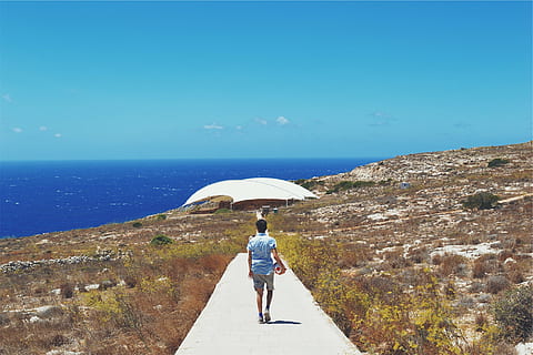 person, blue, shirt, walking, concrete, pathway, day, man, button, near, body, water, daytime, sky, ocean, sea, guy, soccer ball, path, tent, plants, coast, shorts, sunshine, sunny, summer, rear view, horizon over water, full length, adult, clear sky, one person, outdoors, leisure activity, lifestyles, nature, real people, horizon, scenics - nature, 1080P