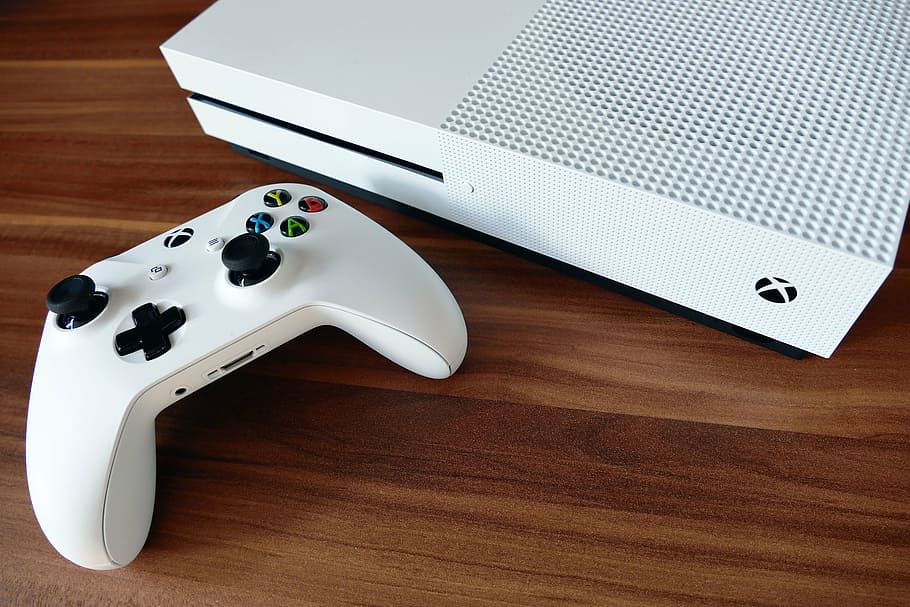 xbox, un, consola, al costat, controlador, x caixa, joypad, activitat, blau, botó, color, ordinador, control, elèctric, entreteniment, equipament, dit, diversió, joc, coixinet de joc, jocs, mà, ordinador de mà, celebració, joia, arcade, joystick, oci, coixinet, perifèric, plàstic, jugar, botó de reproducció, empenta, blanc, jugador, mitjans de comunicació, x-box one, joguines, electrònica, tecnologia, taula, tir de l'estudi, cap gent, a l'interior, primer pla, dia, material de fusta, natura morta, equips informàtics, comunicació, connexió, vista d’angle alt, tecnologia sense fils, cultura i entreteniment artístic, portàtil, Color blanc, color negre, marró, color plata, equipament elèctric, 5K