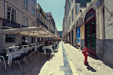 people site, outside, restaurant, alfresco, dining, People, Lisbon, Portugal, alfresco dining, urban, street, architecture, urban Scene, town, city, europe, cityscape, building Exterior, old, house, travel, outdoors, built Structure, tourism, cobblestone, cultures, alley, travel Destinations, narrow, famous Place, history, italy, day, building, sunlight, nature, seat, chair, incidental people, direction, the way forward, footpath, residential district, transportation, diminishing perspective, shadow, 4K