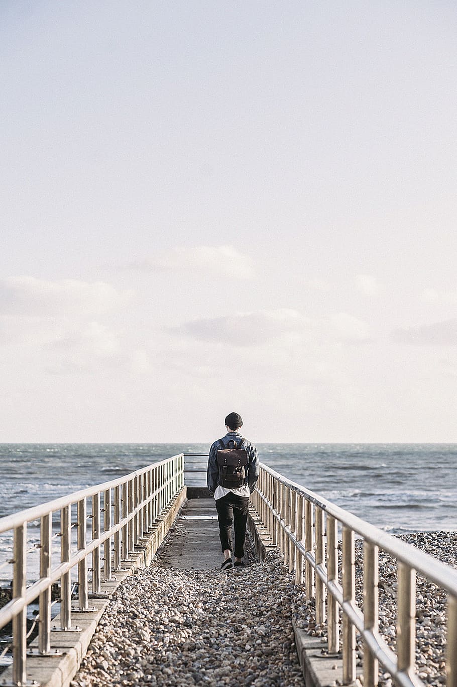 mand, sort, jakke, gå, grå, beton, dok, rygsæk, taske, strand, grus, horisont, landskab, fritid, ocean, udendørs, person, rækværk, rekreation, klipper, sand, hav, marinemaleri, kysten, kyst, ensomhed, sommer, sol, rejse, ferie, vand, bølger, have på, himmel, rigtige mennesker, livsstil, skønhed i naturen, fuld længde, fritidsaktivitet, en person, stående, horisont over vand, scenics - natur, natur, dag, herrer, bagfra, kigger på visning, 4K