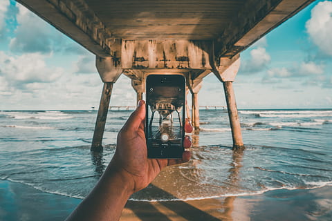sea, sky, beach, hand, camera, clouds, dock, fingers, ocean, photography, picture taking, pier, seafoam, water, waves, connection, photography themes, human hand, nature, holding, one person, wireless technology, photographing, communication, technology, real people, smart phone, day, mobile phone, portable information device, outdoors, horizon over water, 5K, CC0, public domain, royalty free