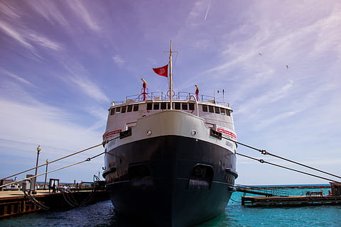 white, black, ship, body, water, near, dock, daytime, boat, ocean, sea, pier, marina, harbour, harbor, blue, sky, clouds, sunshine, nautical vessel, flag, cloud - sky, patriotism, outdoors, no people, day, transportation, mode of transportation, nature, freight transportation, business, shipping, architecture, industry, passenger craft, sailboat, 5K