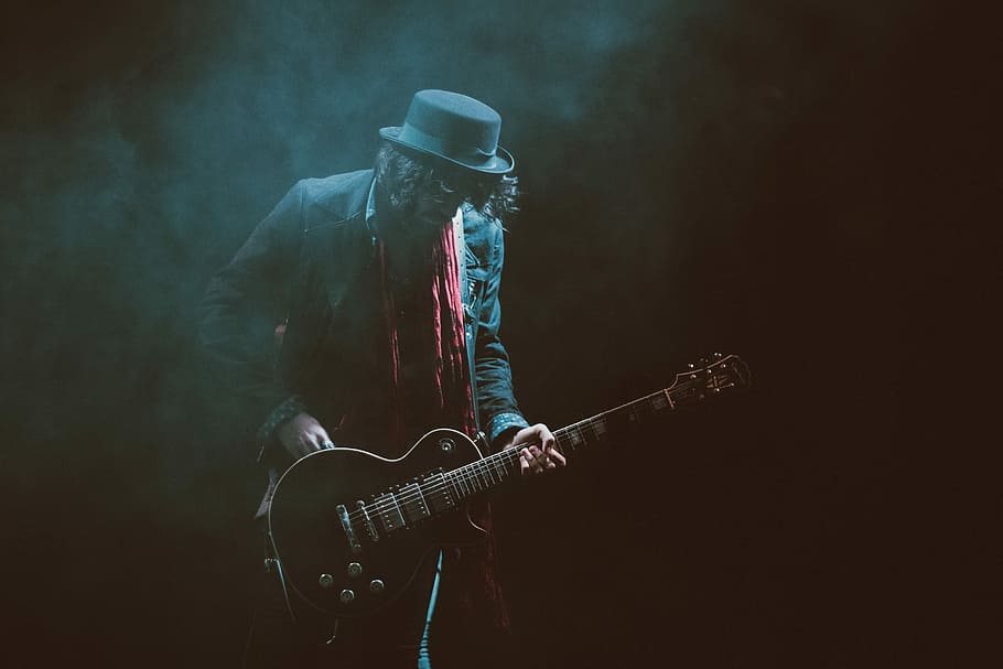 Person, tragen, Anzugjacke, Fedorahut, spielen, Gitarre, Musik-, Musiker, Gitarrist, Rockmusik, Musikinstrument, elektrische Gitarre, Menschen, Kunst und Unterhaltung, eine Person, Männer, Performance, Popmusiker, Künstler, dunkel, Veranstaltung für darstellende Künste, Konzert der populären Musik, Bühne - Aufführungsraum, Unterhaltung, Nur ein Mann, Nur Männer, Rauch - physische Struktur, Kunst, Kultur und Unterhaltung, Saiteninstrument, Musikausrüstung, Bühne, Veranstaltung, moderner Rock, ein Instrument zupfen, Nachtleben, schwarzer Hintergrund, Mikrofonständer, Konzert, 5K