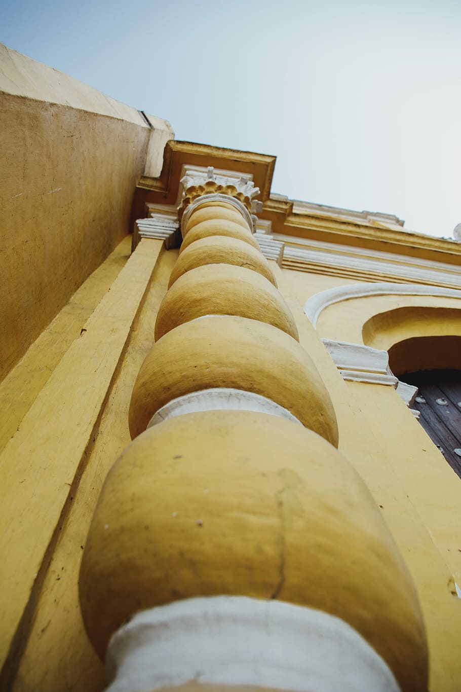 ull de cuc, vista, pilar, baix, fotografia d'angle, columna espiral, arquitectura, columna, groc, edifici, guix, vista d’angle baix, estructura construïda, cel, cap gent, exterior de l'edifici, dia, naturalesa, a l'aire lliure, material de fusta, cel clar, història, el passat, columna arquitectònica, en fila, espiritualitat, indústria, centrar-se en fons, directament a sota, 5K