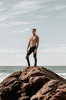 man, black, pants, standing, hill, rock, daytime, flex, cloud, gold, beach, sky, sea, tattoo, good, hot, ab, jeans, ripped, model, male, water, rock - object, one person, shirtless, solid, full length, young men, young adult, land, front view, day, leisure activity, nature, horizon over water, outdoors, shorts, 5K, CC0, public domain, royalty free