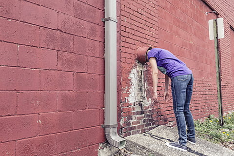 person, wearing, purple, shirt, blue-washed jean, inserting, inside, wall, blue, jean, people, whimsical, lazy, sad, silly, goofy, building, lady, girl, strange, weird, humor, red, stuck, outdoors, brick, one Person, men, urban Scene, wall - Building Feature, males, brick wall, full length, adult, human arm, casual clothing, architecture, built structure, real people, lifestyles, day, standing, building exterior, bending, side view, jeans, 5K