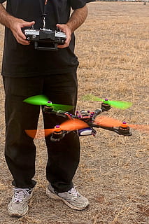 person, controlling, black, quadcopter drone, quadcopter, drone, remote control, multi rotor, robot, flying, unmanned, multirotor, uav, remote, quadrocopter, multicopter, real people, sport, men, lifestyles, people, leisure activity, day, occupation, holding, camera - photographic equipment, photography themes, low section, technology, land, activity, nature, skill, outdoors, human body part, photographer, digital camera, 1080P, CC0, public domain, royalty free
